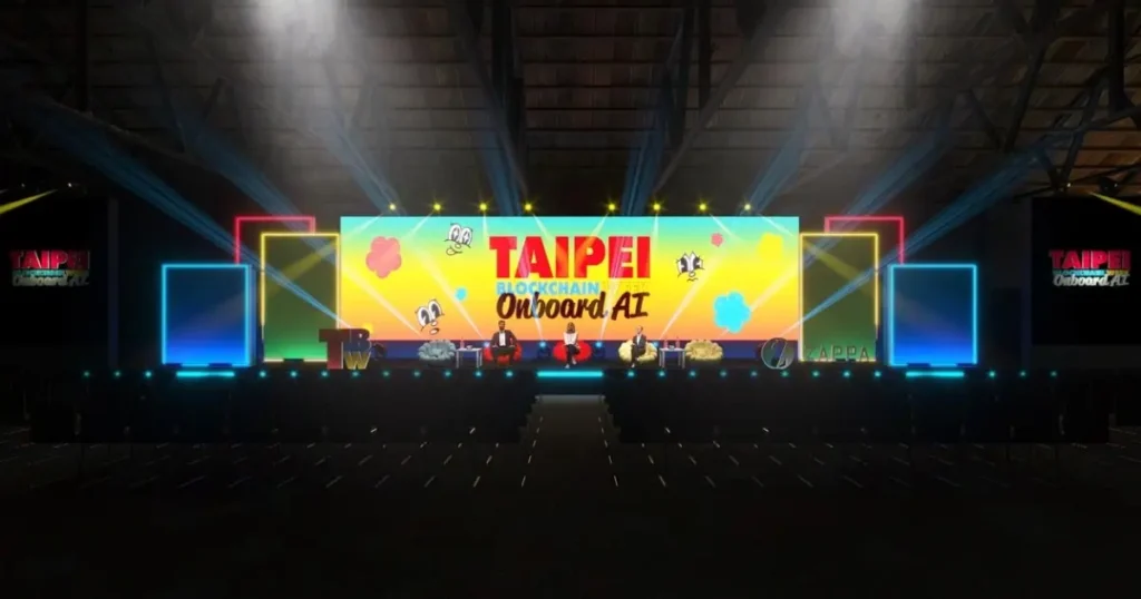 TBW2025のメインステージは松山文創園区に設置され、カラフルな「Taipei Blockchain Week Onboard AI」を背景に、BABY BLO$$OMSのマスコット、ブルーの照明、倉庫会場の複数のスクリーンが映し出された。